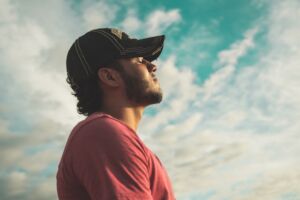 man with eyes closed with cloudy sky behind him