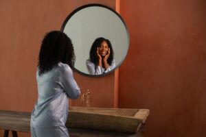 woman of color smiling at self in mirror
