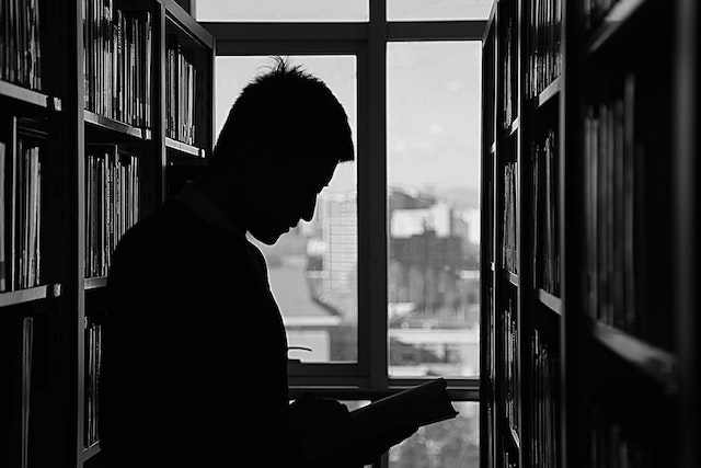 silhouette of a man reading in a library