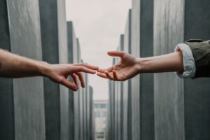 two people reaching their hands out for one another with only arms showing in photo