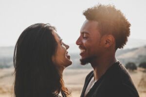 photo of a man and woman smiling at each other while standing on a beach