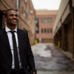 photo of a smiling man wearing a business suit standing in an alleyway