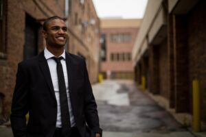photo of a smiling man wearing a business suit standing in an alleyway