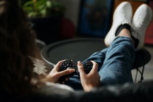 photo of a person holding a video game controller in their hands with feet propped up on a table