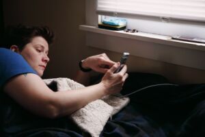 photo of a person laying in bed staring at their phone