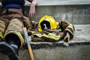 photo of a firefighter sitting on a stone step with their helmet and protective gear next to them