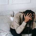 image of a man of color sitting on a couch who is crying and in distress
