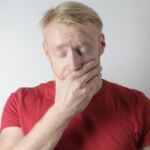 photo of a man who looks anxious holding his hand up to his mouth with eyes closed
